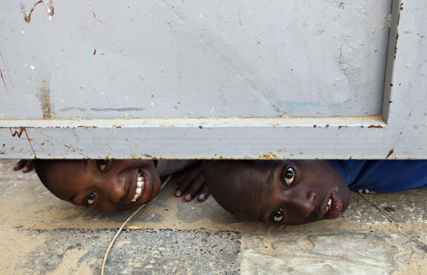 weird sport: Boys trying to catch a glimpse under a door at a stadium