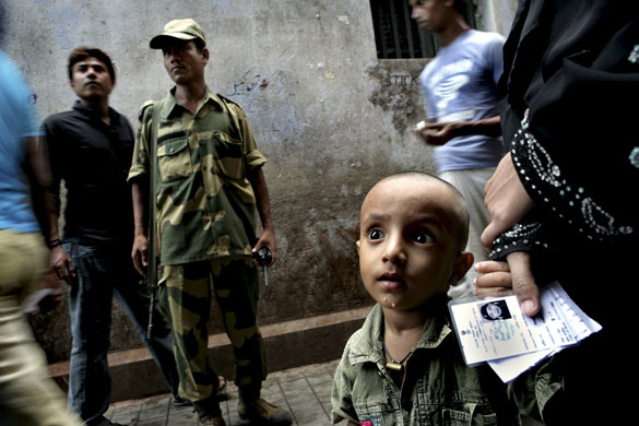 India Elections 5th Stage: A security guard guides Indian voters to a polling station in Calcutta