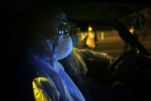 14 May 2009: Beijing, China: Health personnel transport passengers to quarantine