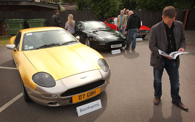Week in business: Buyers look at a line of of Aston Martin cars.