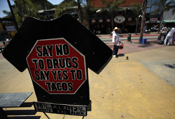 24 hours in pictures : A street vendor walks next to a taco restaurant in Tijuana, Mexico