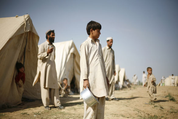 24 hours in pictures : Pakistan: people wait for food to be delivered at a refugee camp 