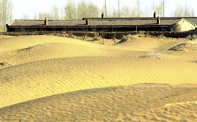 Minqin China: Photo shows an abandoned house facing the approaching desert