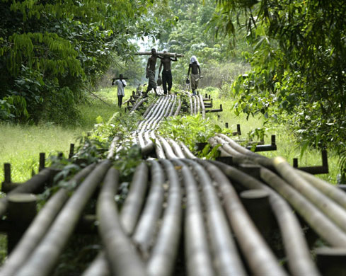 Shell in the Niger Delta: Local youths walk on oil pipeline belonging to Shell in Utorogun, Nigeria.