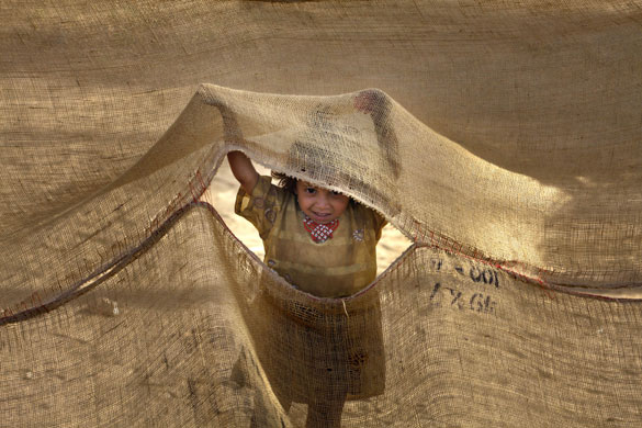 20 May 2009: Swabi, Pakistan: A girl peers through a tent in Chota Lahore Refugee Camp