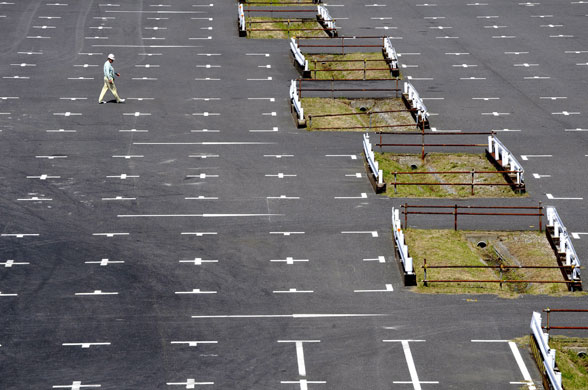 20 May 2009: Tokyo, Japan: A worker walks through an empty parking space