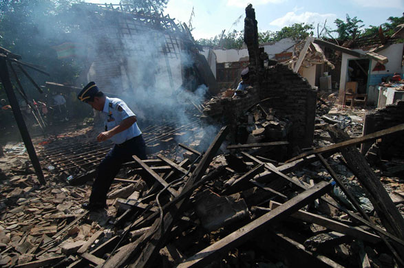 Plane crash in Indonesia: An air force official walks among the ruin of houses damaged by the plane