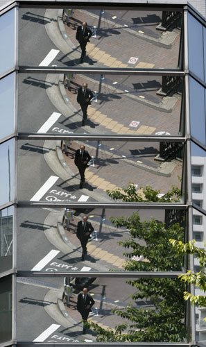 Week in Business: A businessman is reflected on an office building in Tokyo, Japan.