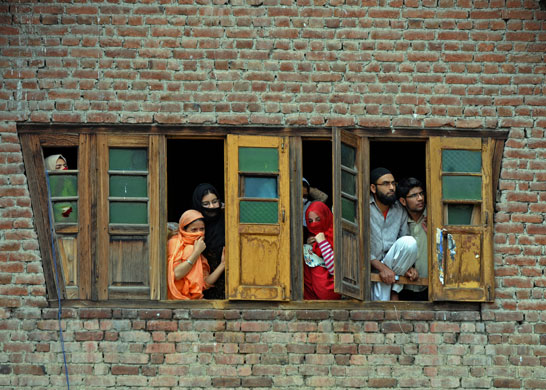 22 May 2009: Srinagar, India: Bystanders watch from the upper floors of a building