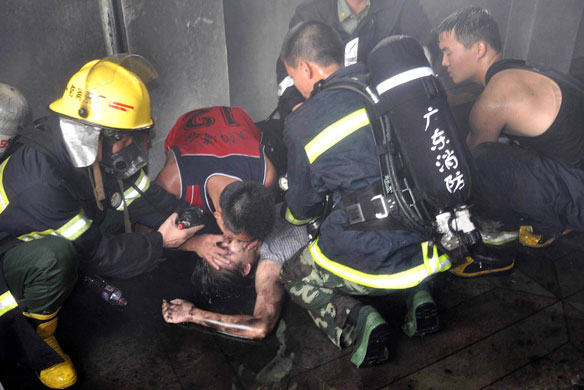 22 May 2009: Shantou, China: Firefighters try to save a victim of a factory fire