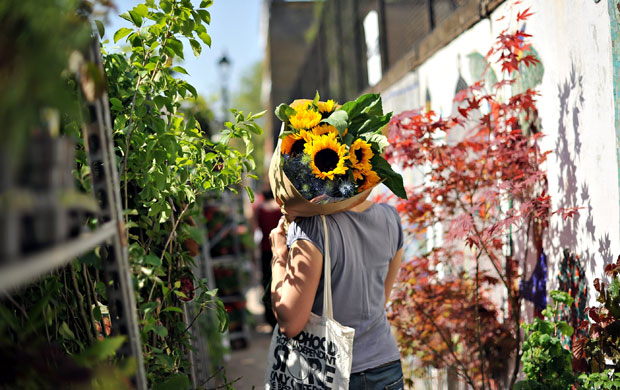 24 hours in pictures: London: A woman carries sunflowers at the Columbia Road flower market