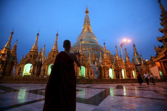 24 hours in pictures: Rangoon, Burma: A Buddhist monk takes a photo of the Shwedagon Pagoda 