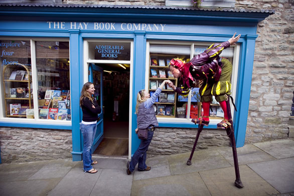 Hay Festival 2009: A jester on stilts proposes to a passerby outside a book shop in Hay-on-Wye