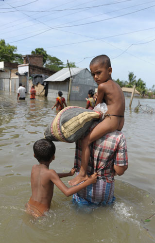 Cyclone Aila: Sandeshkhali, India: A villager carries his child to safety 