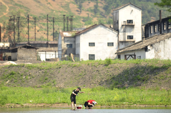 North Korea : Two North Korean women wash their hair in the Yalu River