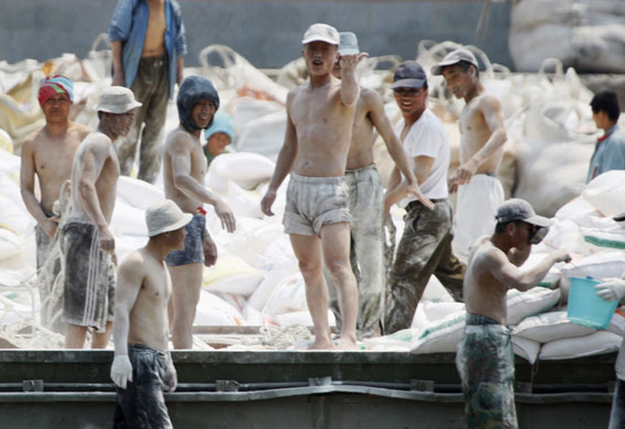 North Korea : North Korean dock workers react to a passing Chinese tour boat