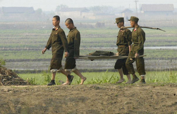 North Korea : North Korean soldiers walk along the banks of the Yalu River near Sinuiju