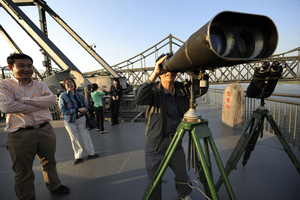 North Korea : Chinese tourists use telescopes on 'Broken Bridge' 