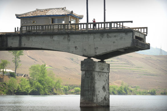 North Korea : A North Korean waves from a bridge destroyed during the Korean war