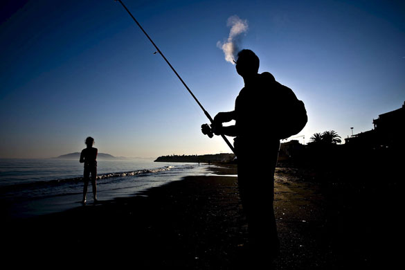 24 hours in pictures: An angler enjoys a smoke as he fishes at dusk in Malaga