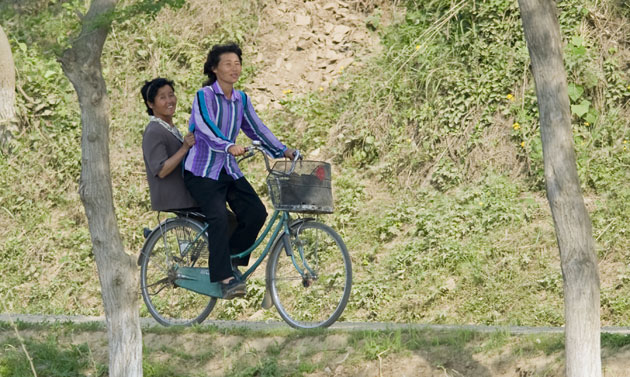 North Korea Border: Women ride a bike along the border between North Korea and China