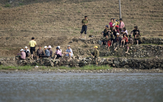North Korea Border: North Korean workers sit on the riverside at the international border