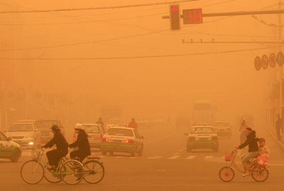 6 May 2009: Hetian, China: Residents ride bicycles during a sandstorm