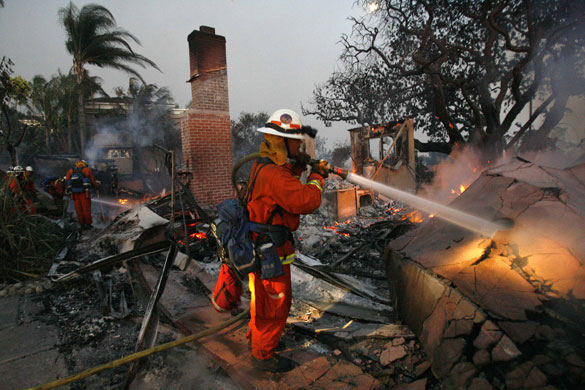 California Wildfires: Firemen spray water on a house burning