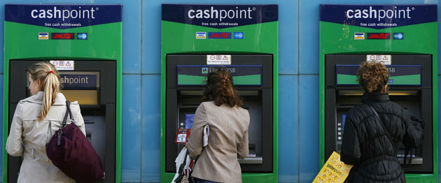 Business week in pictures: Women use a Lloyds ATM machine