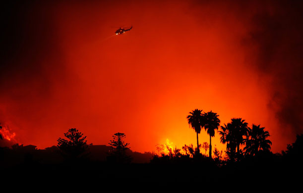 California Wildfires: A firefighting helicopter makes night drops in a canyon