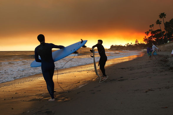 California Wildfires: Surfers enter the water under heavy smoke from the Jesusita fire