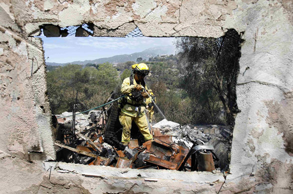 California Wildfires: A firefighter sprays water on the rubble of a house