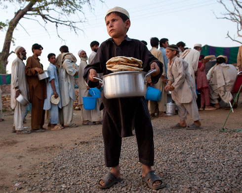 IDP camps Pakistan: A Pakistani boy holds a pot of meat curry
