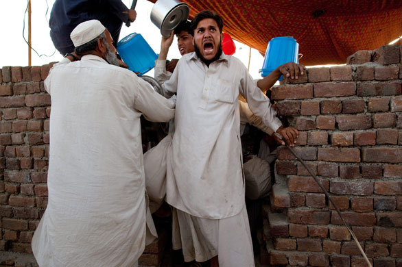 IDP camps Pakistan: A kitchen guard yells as he pushes back a hostile crowd