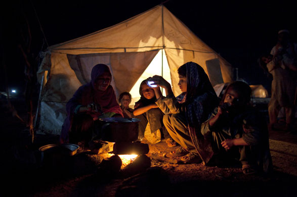 IDP camps Pakistan: Women cook their dinner over a fire in Jalozai camp