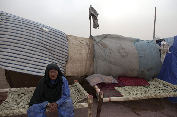 IDP camps Pakistan: Bibi, 70, sits outside her tent as the wind and dust blows in Jalozai camp