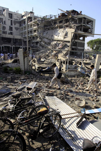 Peshawar bombing: People walk through the destruction of the Peshawar Pearl Continental 