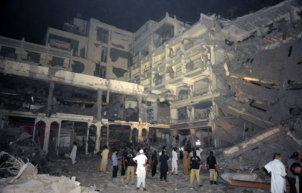 Peshawar bombing: Pakistani police gather beside the destroyed Pearl Continental hotel 