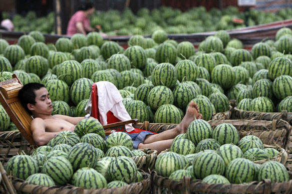 24 hours: Shanghai, China: A young watermelon vendor uses his mobile phone