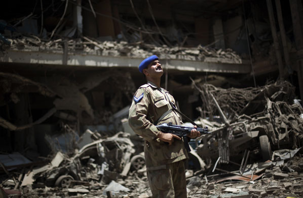 24 hours: Peshawar, Pakistan: A soldier inspects the debris of the Pearl Continental