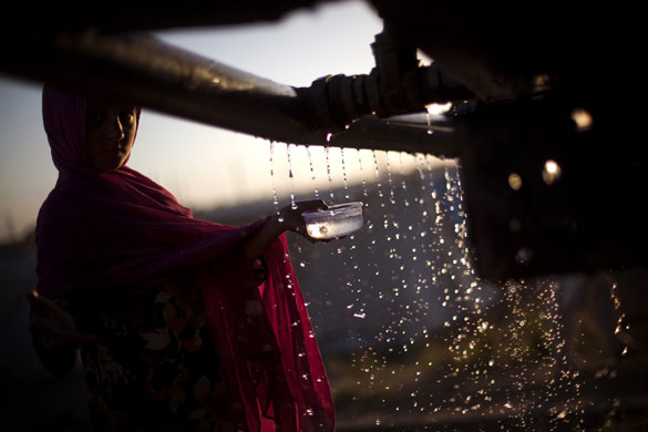 24 hours: Pakistan: A displaced Pakistani girl collects water from a water truck