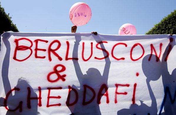Gaddafi in Rome: Demonstrators hold a banner against Berlusconi and Gaddafi