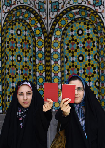 Elections in Iran: Women show their certification cards at a polling station in Qom