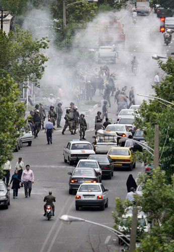 Riots in Tehran: Iranian riot police stand in front of a cloud of tear gas 
