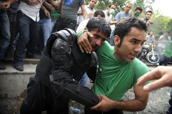 Riots in Tehran: A protestor helps evacuate an injured Iranian riot-police officer