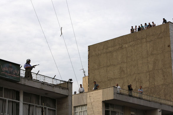 Iran protests: A member of a pro-government militia stands guard on a rooftop
