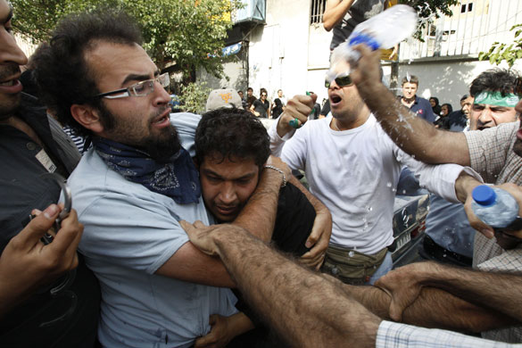 Iran protests: A suspected member of a pro-government militia is taken away from a rally