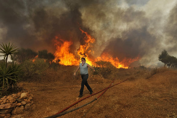 24 hours: Athens, Greece: A man walks away from the flames of a fire