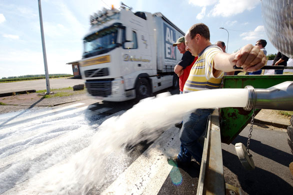 24 hours: Bettignies, France: A dairy farmer dumps milk onto the street