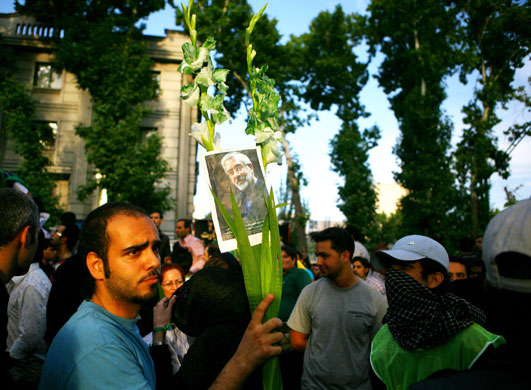 Iranian protests: A supporter Mousavi holds up flowers and a picture Mousavi